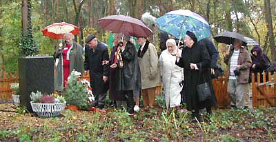 Teilnehmer der Eröffnungsfeier legen nach jüdischer Tradition kleine Steine zur Erinnerung an die Toten auf den Gedenkstein.